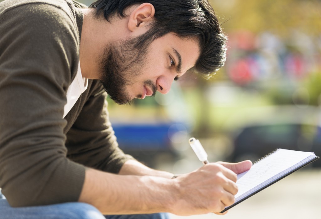 S+ Close-up of a young man writing his journal outdoors. Istanbul iStockalypse 2014 Pitch Shoot.