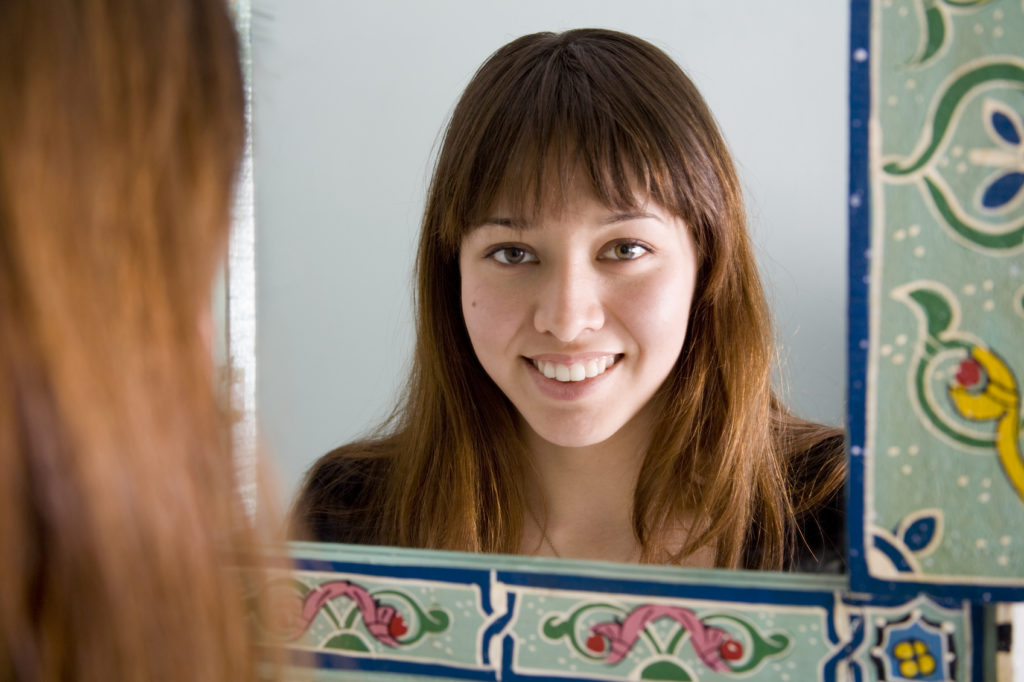 Attractive young woman seen as a reflection in an ethnic style mirror.