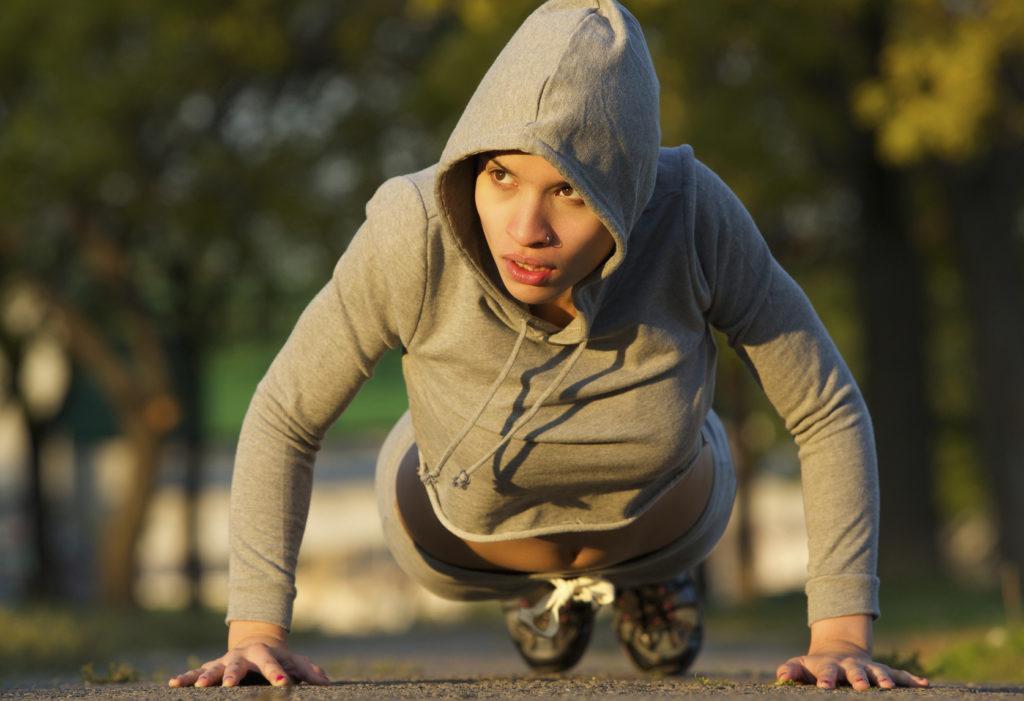 Portrait of an attractive young woman doing push ups outdoors