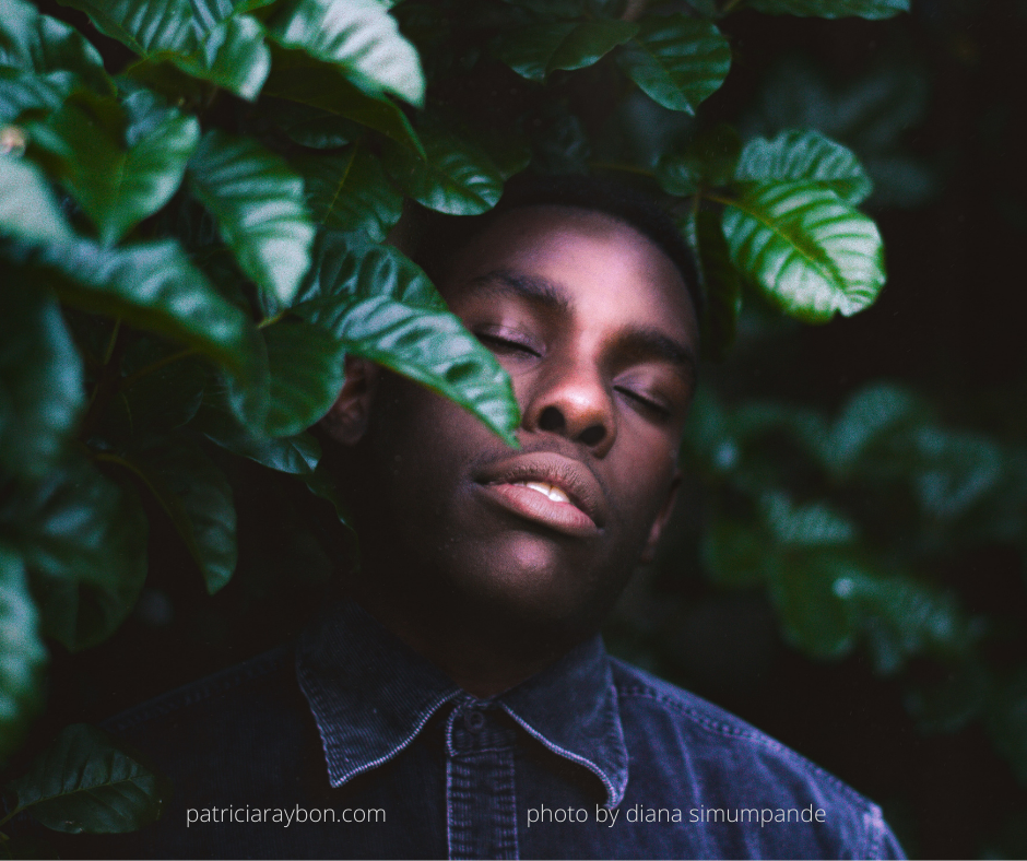 photo of young black man resting amid green trees in a serene setting
