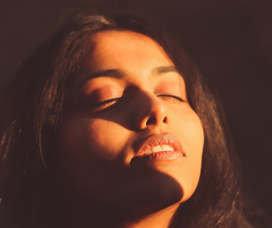 Photo of young woman facing the sunshine with her eyes closed, as she ponders letting God lift her head for blog post on that subject.